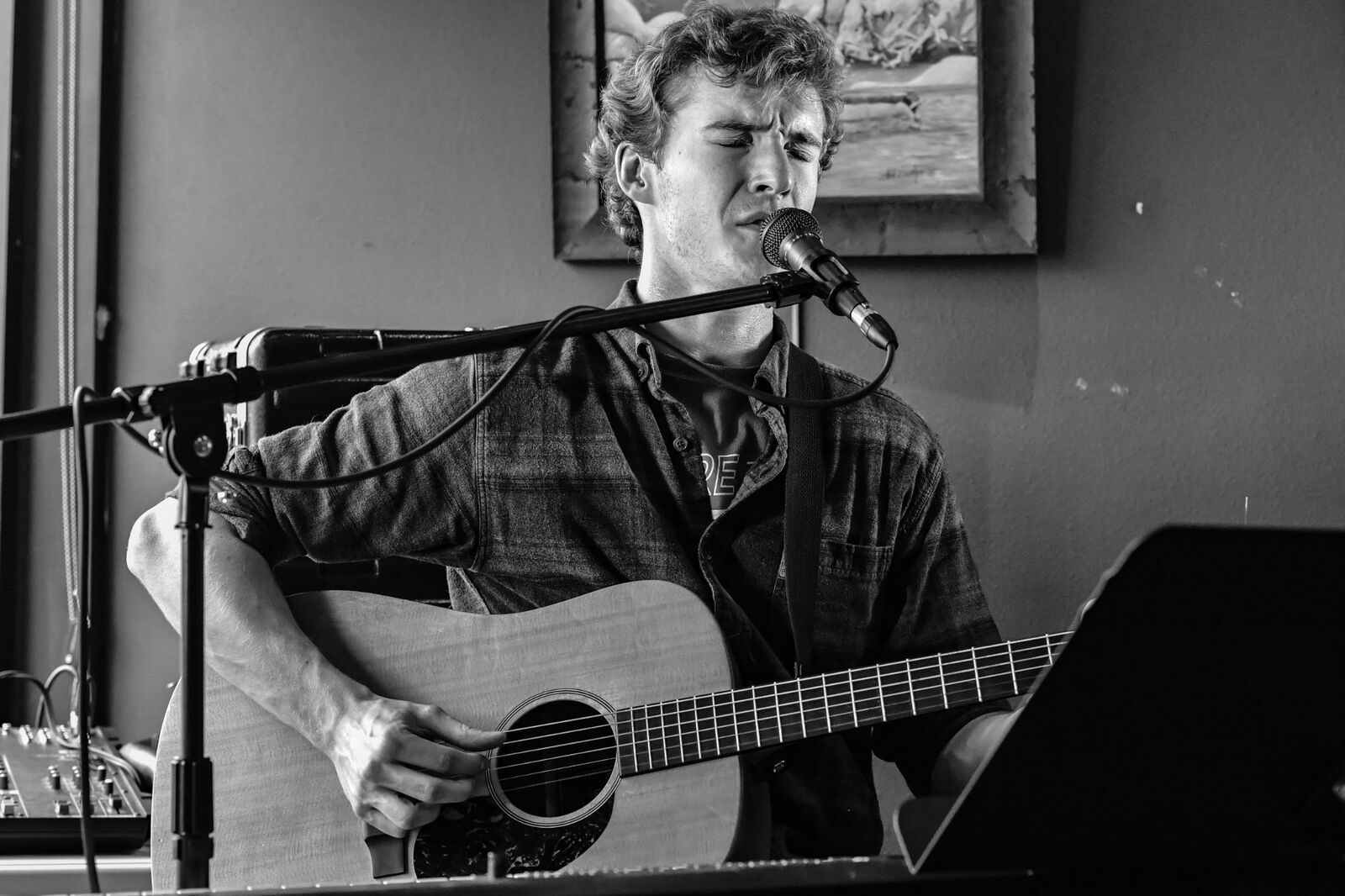 Ryan Howe singing with acoustic guitar, black and white portrait at a venue