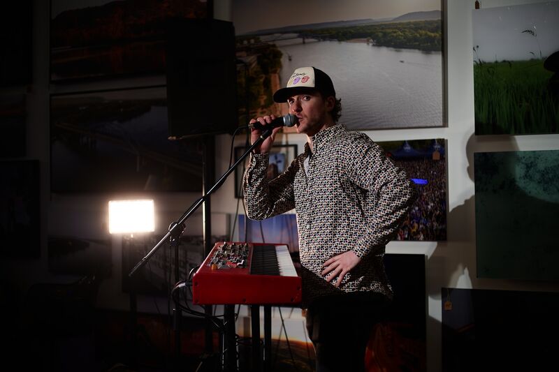Ryan Howe singing with handheld microphone at an art gallery performance